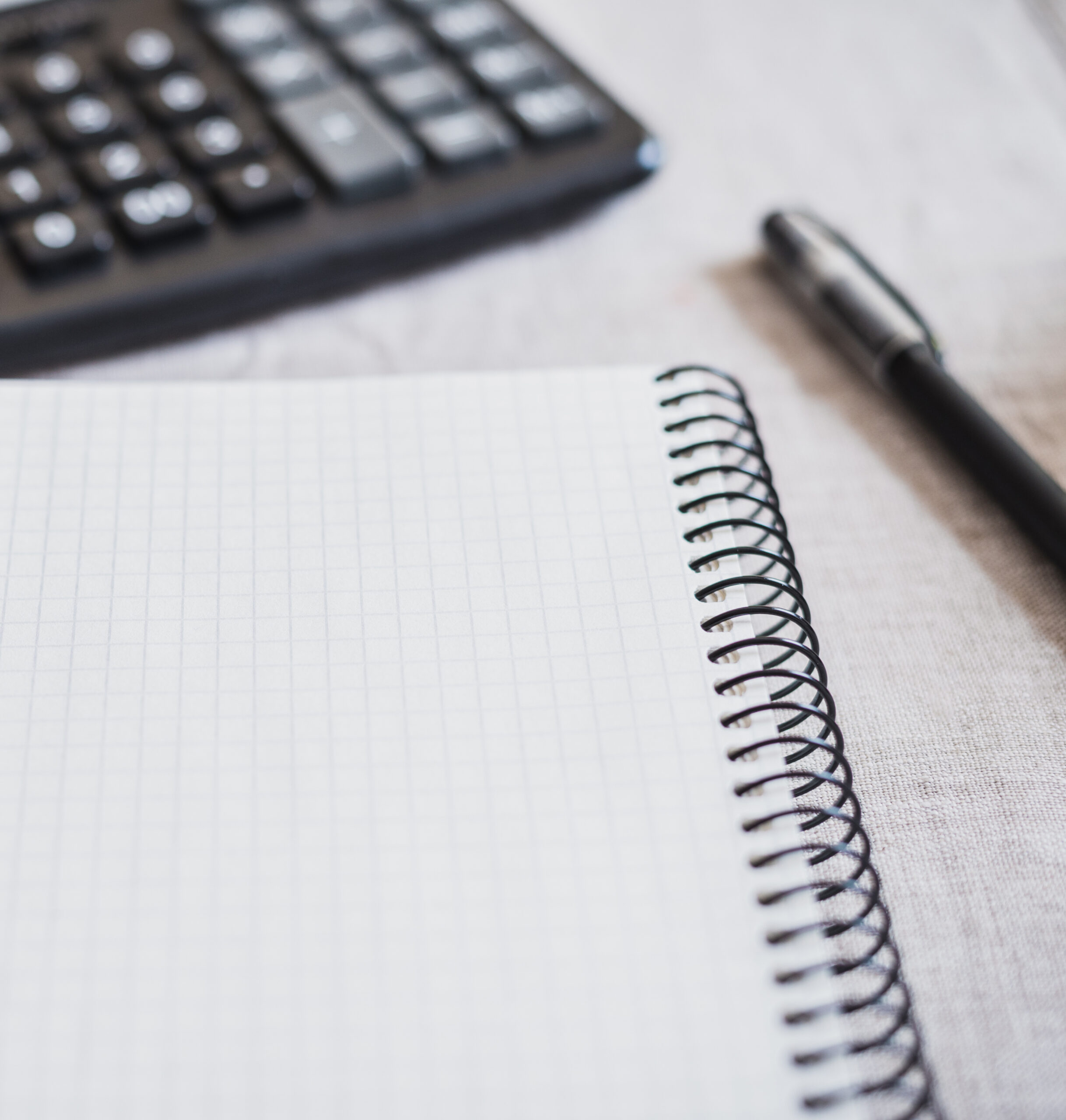 Phone, notebook and calculator lie on a fabric background. Horizontal frame paper, pen, and calculator